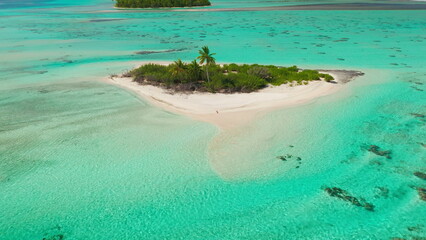 Young woman tanning on sand beach wild tropical island surrounded by coral reef atoll. Wild untouched nature landscape. Outdoor lifestyle travel on summer holiday vacation. Aerial drone shot