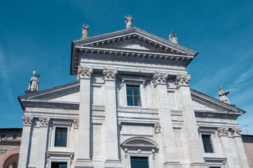 White cathedral with grand doors, small statues, and windows in the province of Pesaro and Urbino