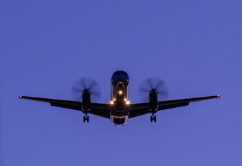 Plane preparing to land at the airport against a blue sky at night
