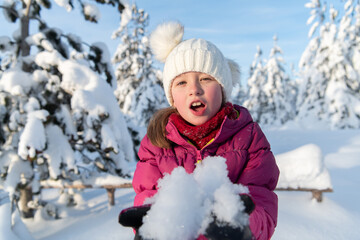 Fototapeta premium A Sweet Girl's Playful Adventure in the Sun-Kissed Snowy Mountains.