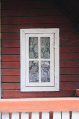 White window on a red wooden house