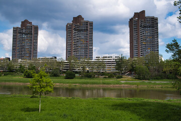Obraz premium Park adjacent to urban skyscrapers along a riverbank, Manheim, Germany