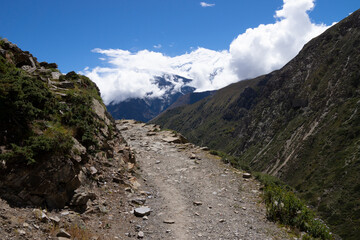 a dirt road runs through a wide valley with high mountains