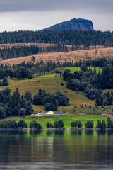 a scenic landscape view of trees, grassy land and house across the river