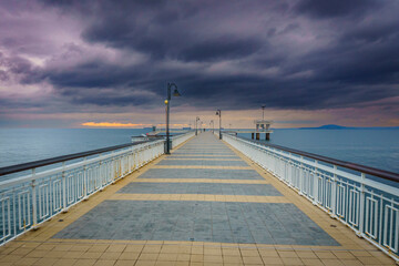 Obraz premium Pier extending into the water at sunset.