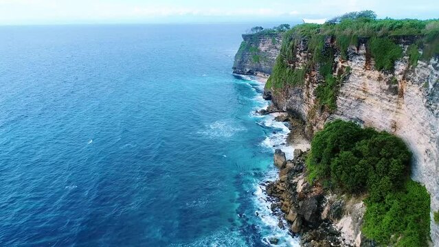 Aerial view of rocky cliffs and blue ocean with big waves
