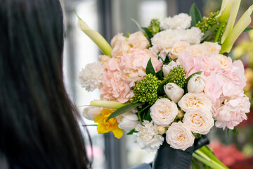 close up flower shop girl near a white table collects a flower arrangement of a beautiful bouquet of white flowers