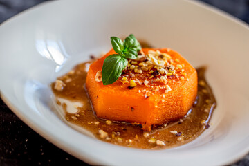 Sliced roasted pumpkin with honey and walnuts on a white plate