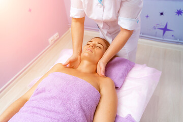 Relaxing massage. European woman getting facial massage in spa salon, side view