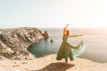 Woman green dress sea. Female dancer posing on a rocky outcrop high above the sea. Girl on the...