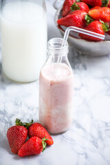 Strawberries and a bowl of milk on a kitchen counter