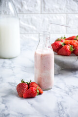 Strawberries surrounding a bottle of milk