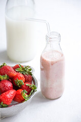 Strawberries served on a plate with a glass of milk