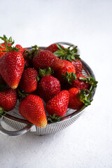 Close-up of a metal colander filled with ripe strawberries