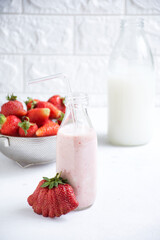 Bottle brimming with fresh strawberries beside a bowl of assorted fruits