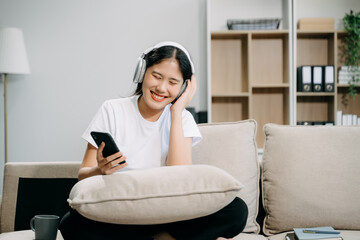 Young asian woman using smartphone and tablet while seated on couch