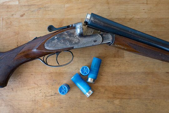 nice old open parallel shotgun with some 12 gauge cartridges on a wooden table