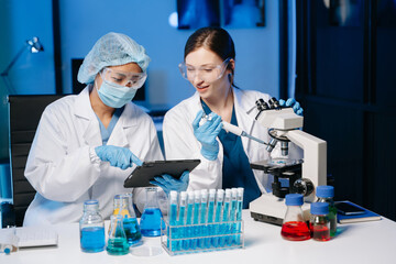 Fototapeta premium Young scientists conducting research investigations in a medical laboratory, a researcher in the foreground is using a microscope in laboratory