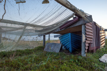 fishing nets and gear are drying on wooden poles on the seashore. evening sun and blue sky