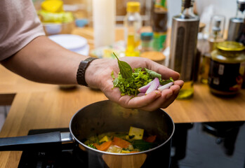 Chef at the kitchen preparing green curry with herbs and rice
