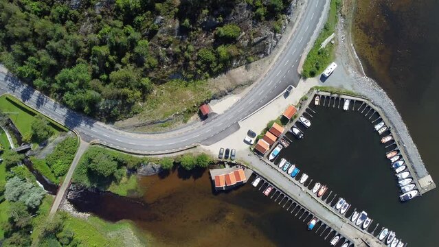 Aerial footage of boats port adjacent a coastal road in Mollosund village in Orust, Sweden