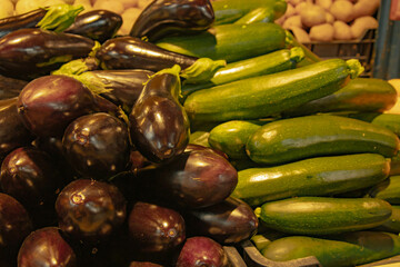 Eggplant and zucchini are like day and night. Fresh, young vegetables fascinate with their beauty. Zucchini and eggplant are lying on the counter and waiting for someone to buy them.