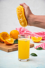 Man is juicing an orange into a glass on a table