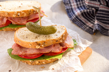 Sandwiches with deli meat and fresh vegetables on a wooden cutting board