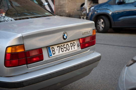 Old BMW 520i 5 series generation E34 in silver color parked on the street of the city of Barcelona
