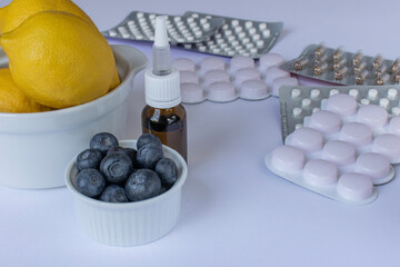 The drops are in a warm glass bottle next to the packages of tablets. White background. Close-up with copy space
