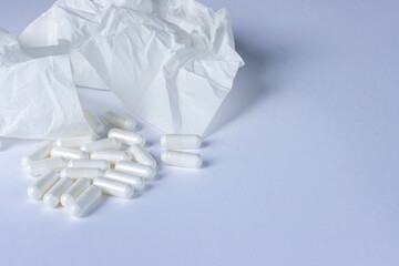 White pills are scattered on a white background. Used nasal tissues are white. Close-up with copy space