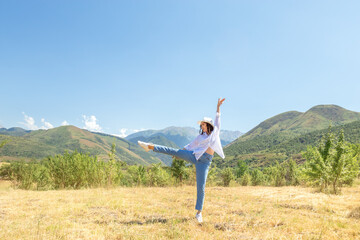 Fototapeta premium Joyful Woman Dancing in Sunny Meadow with Mountains