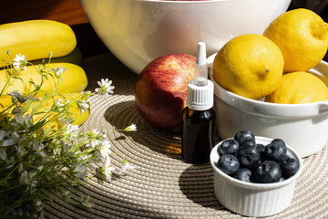 Fruits and berries on the table close-up. Spray in a dark glass bottle with a white cap. Cold kit