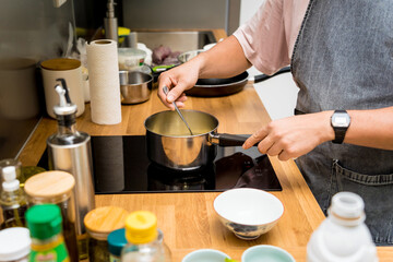 Chef at the kitchen preparing green curry with herbs and rice