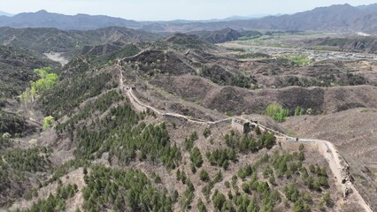 Drone shot of the Great Wall of China showing the hilly terrain next to it.