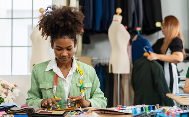 Portrait of young african american woman fashion designer stylish sitting and working with color samples.Attractive young african girl work with colorful fabrics at fashion studio