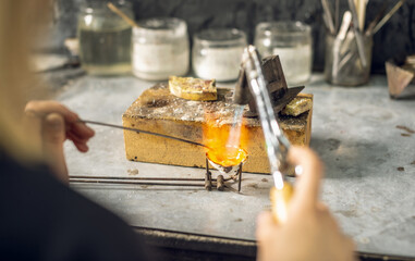 Heating with a flame jet of a metal billet of a silver ring. The work of a jeweler in the workshop