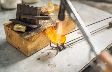 Heating with a flame jet of a metal billet of a silver ring. The work of a jeweler in the workshop