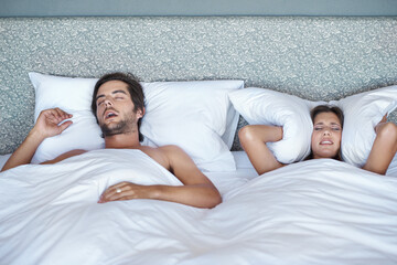 Woman, stress and man snore in bed, sleeping and annoying noise or pillow to cover ears in home....