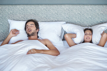 Woman, stress and man snore in bed, sleeping and annoying noise or pillow to cover ears in home. Couple, block sound and audio from wife nap or dreaming, insomnia and frustrated or exhausted rest