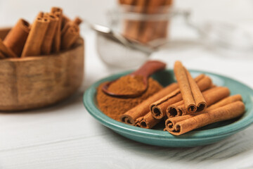 Cinnamon sticks on a textured wooden background. Cinnamon roll. Spicy spice for baking, desserts and drinks. Fragrant ground cinnamon. cinnamon powder Close-up. Place for text. copy space