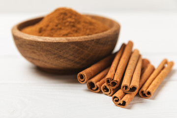 Cinnamon sticks on a textured wooden background. Cinnamon roll. Spicy spice for baking, desserts and drinks. Fragrant ground cinnamon. cinnamon powder Close-up. Place for text. copy space