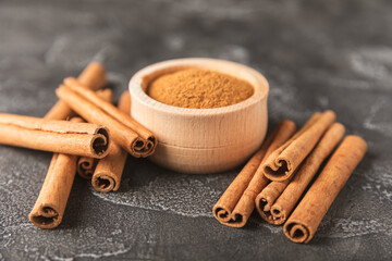 Cinnamon sticks on a textured wooden background. Cinnamon roll. Spicy spice for baking, desserts and drinks. Fragrant ground cinnamon. cinnamon powder Close-up. Place for text. copy space