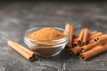 Cinnamon sticks on a textured wooden background. Cinnamon roll. Spicy spice for baking, desserts and drinks. Fragrant ground cinnamon. cinnamon powder Close-up. Place for text. copy space