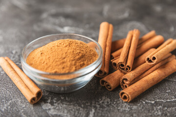 Cinnamon sticks on a textured wooden background. Cinnamon roll. Spicy spice for baking, desserts and drinks. Fragrant ground cinnamon. cinnamon powder Close-up. Place for text. copy space