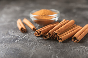 Cinnamon sticks on a textured wooden background. Cinnamon roll. Spicy spice for baking, desserts and drinks. Fragrant ground cinnamon. cinnamon powder Close-up. Place for text. copy space