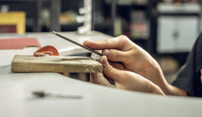 A jeweler uses a file to align a piece of jewelry in the form of a silver ring. Craft in a jewelry...