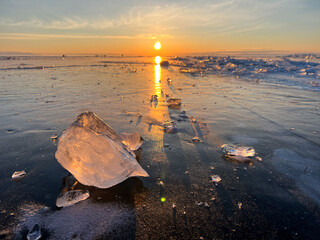 Beautiful sunrise over freezing Baikal water lake in winter season