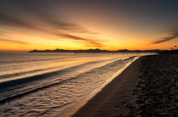 sunrise seascape with an old wooden dock leading out into the calm ocean waters of Alcudia Bay