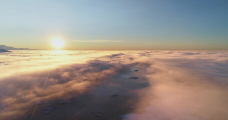 Aerial high altitude flight over morning cloudscape. Sunrise sun shine on bright layers of fluffy...